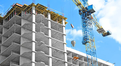 Crane and building under construction against blue sky